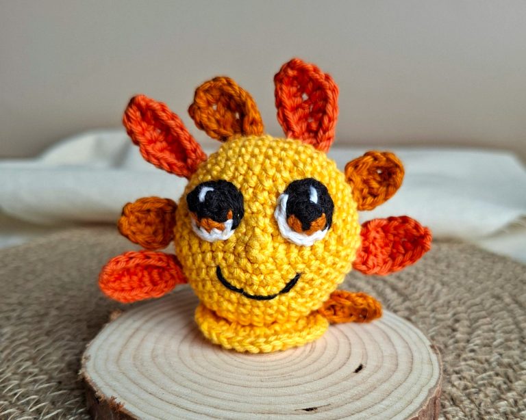 Amigurumi Soléa représentant un petit soleil, incarnant la joie, crocheté à la main dans les tons jaune et orange