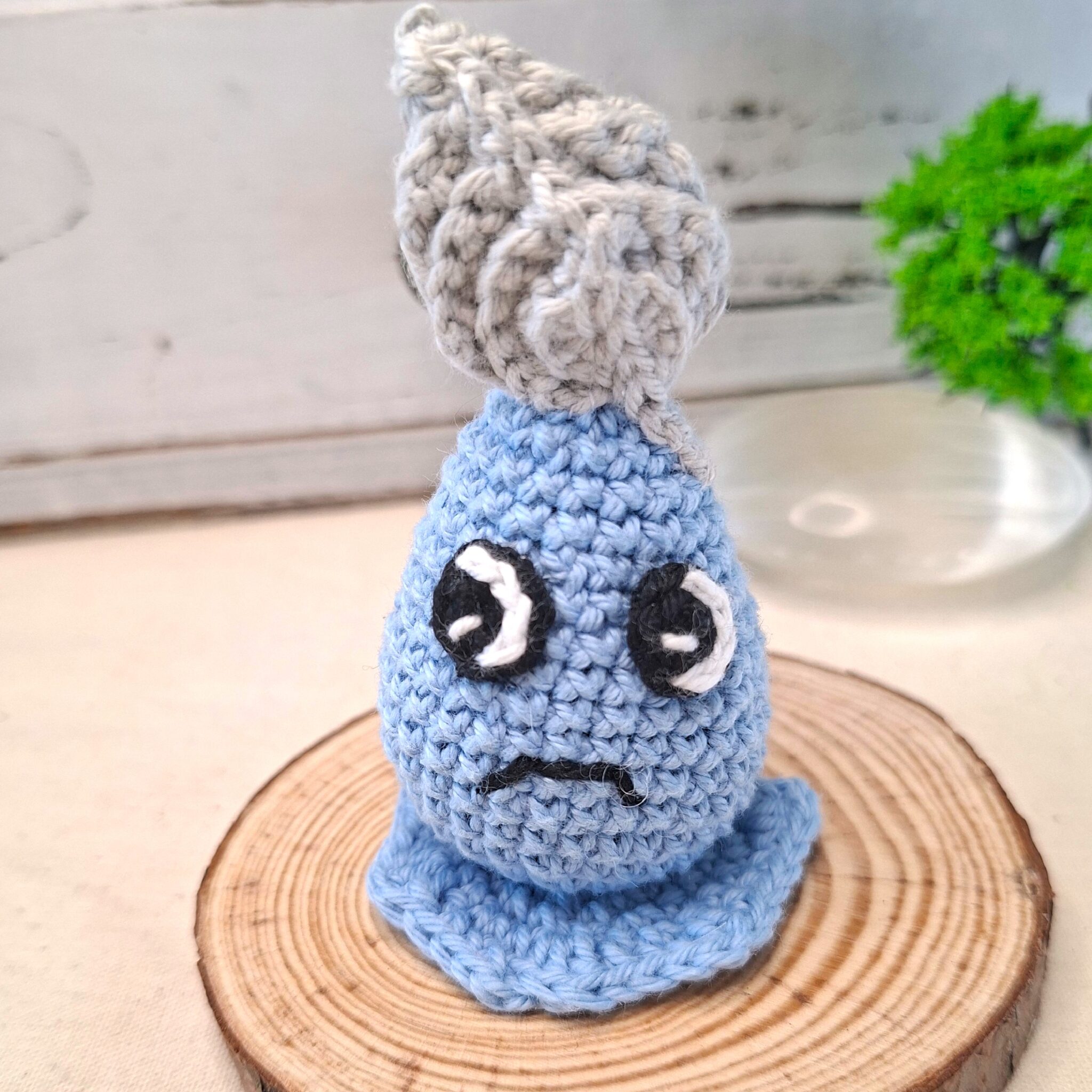 Amigurumi crochet bleu sur socle bois, Plumélia Allégée avec plume et regard expressif