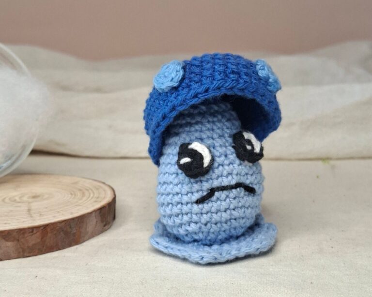 Plumélia, amigurumi crochet tristesse avec casquette bleue, création poétique Émotions Universelles.
