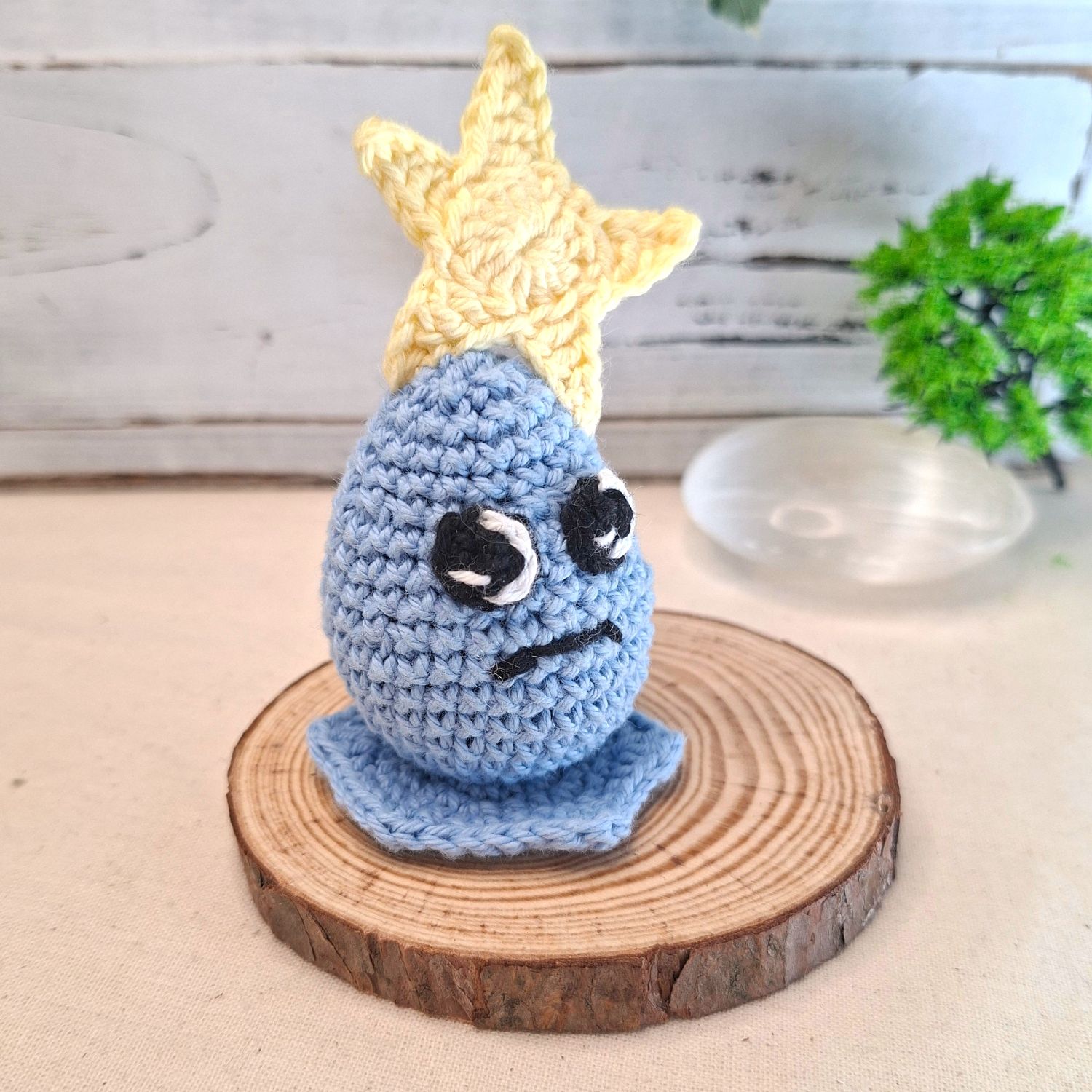 Amigurumi Plumélia Mélancolique — goutte bleue au crochet coiffée d’une étoile jaune, sur socle bois