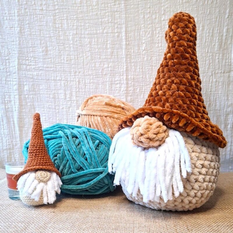 Duo de Naélis, veilleurs d’hiver Clairimagine - l’un crocheté en fil chenille caramel et beige, l’autre en fil coton dans les mêmes tons, tous deux coiffés d’un chapeau pointu et d’une barbe blanche.